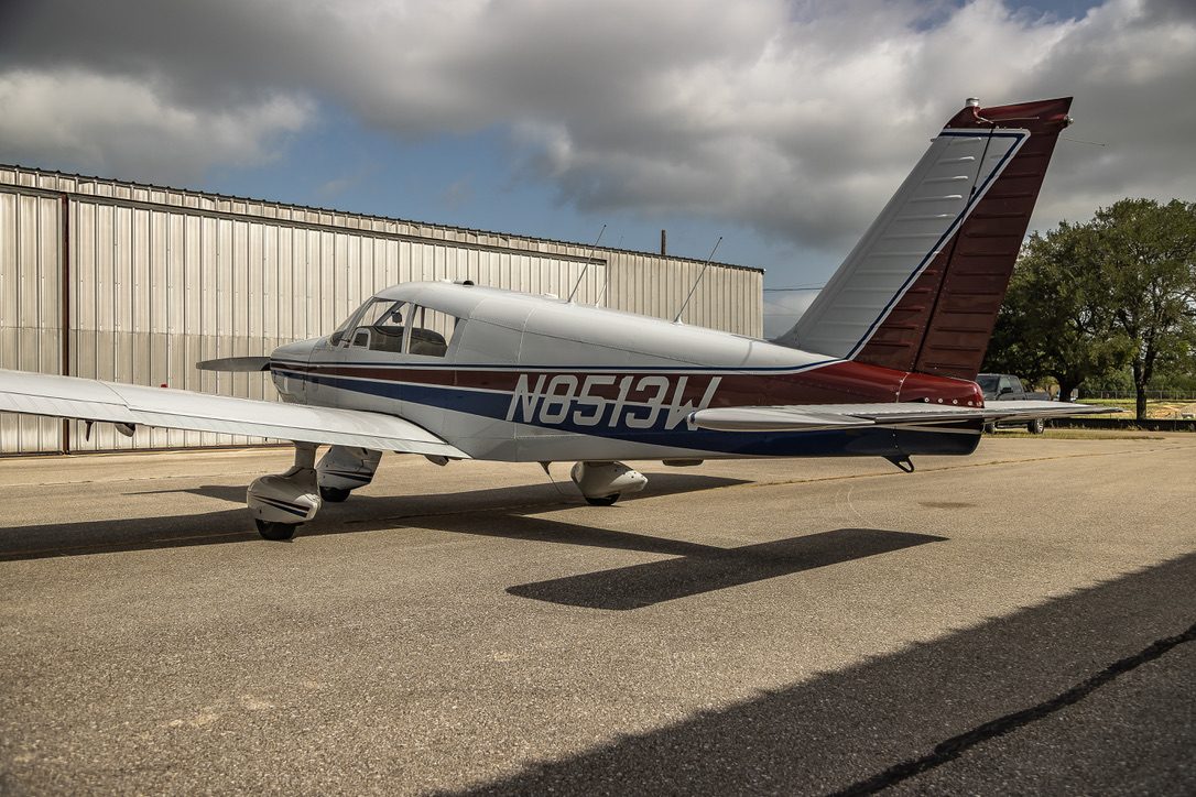 Side view of N8513W, a Piper Cherokee 235, parked by the hangar